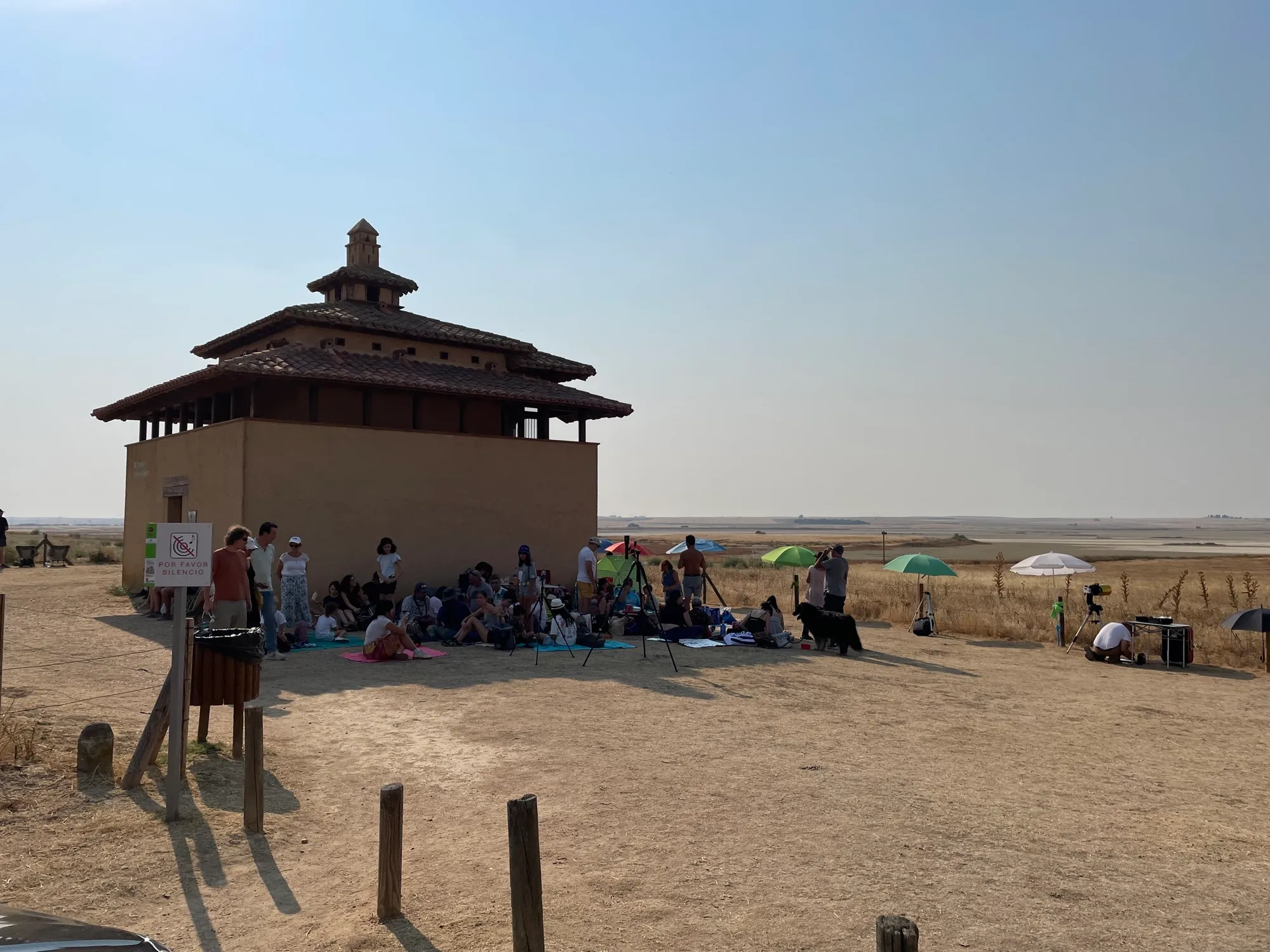 Un grupo de gente resguardada a la sombra del edificio del observatorio, con la laguna al fondo